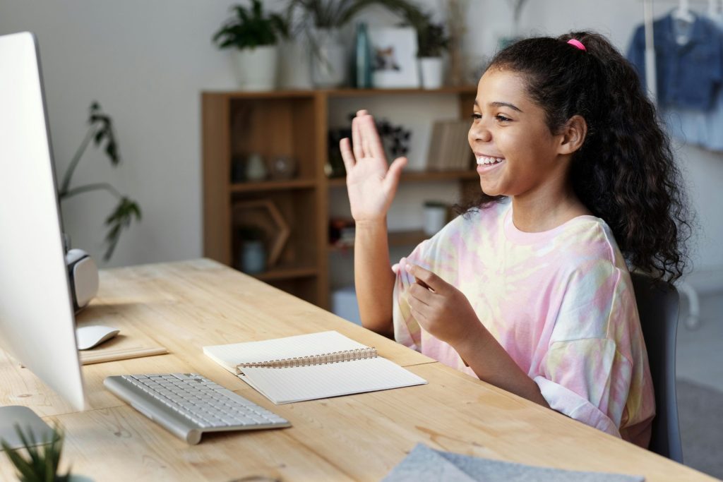 Happy student greeting her French tutor online during a online lesson.